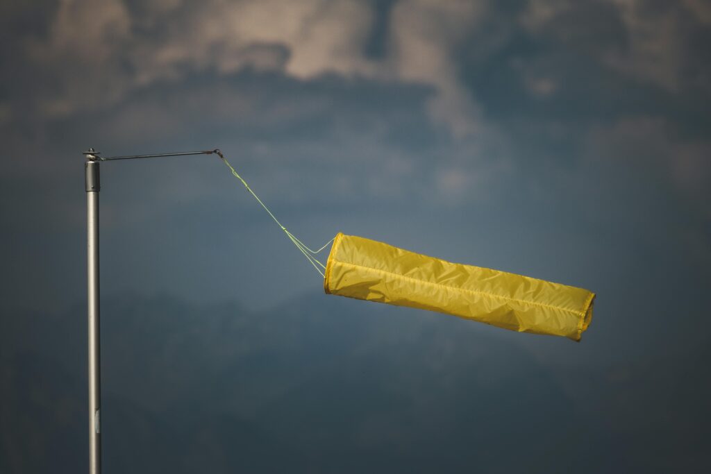 An isolated yellow windsock indicating wind direction against a dark, cloudy backdrop